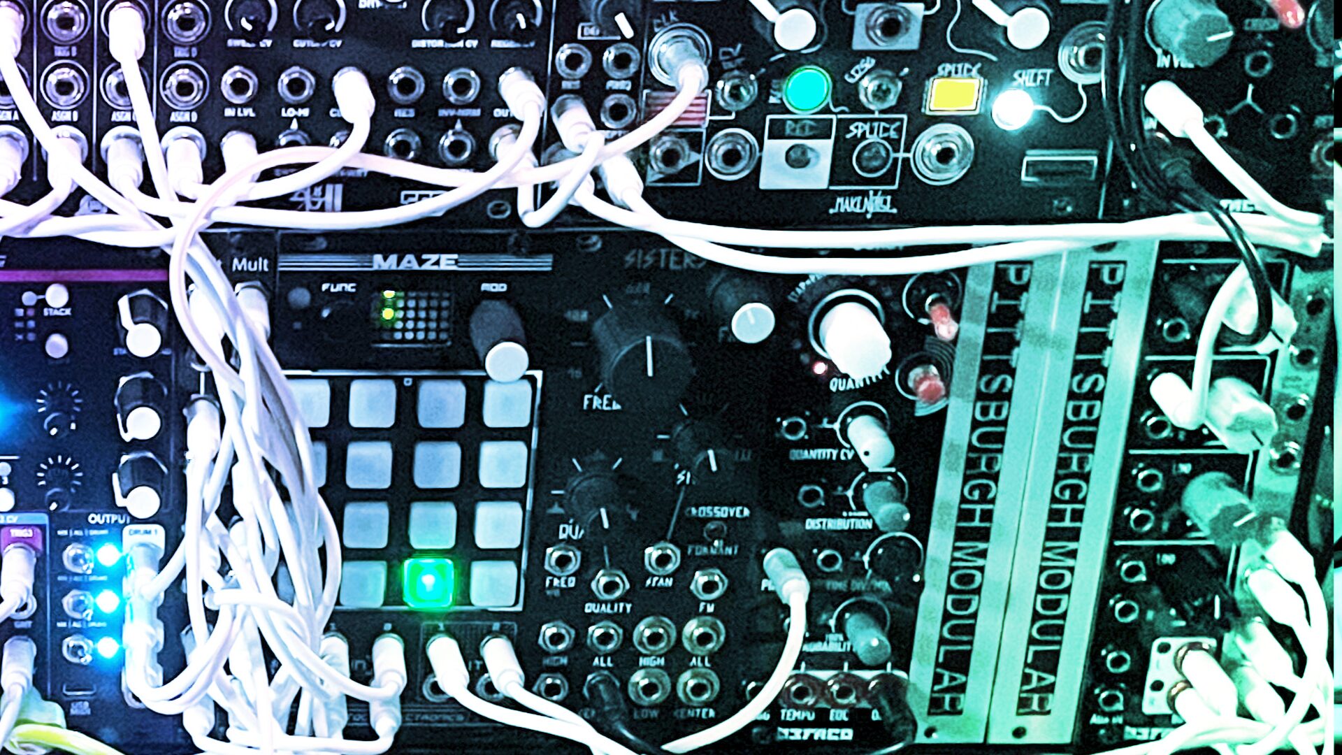 Eurorack system lit in teal with tangled white patch cables and a grid controller