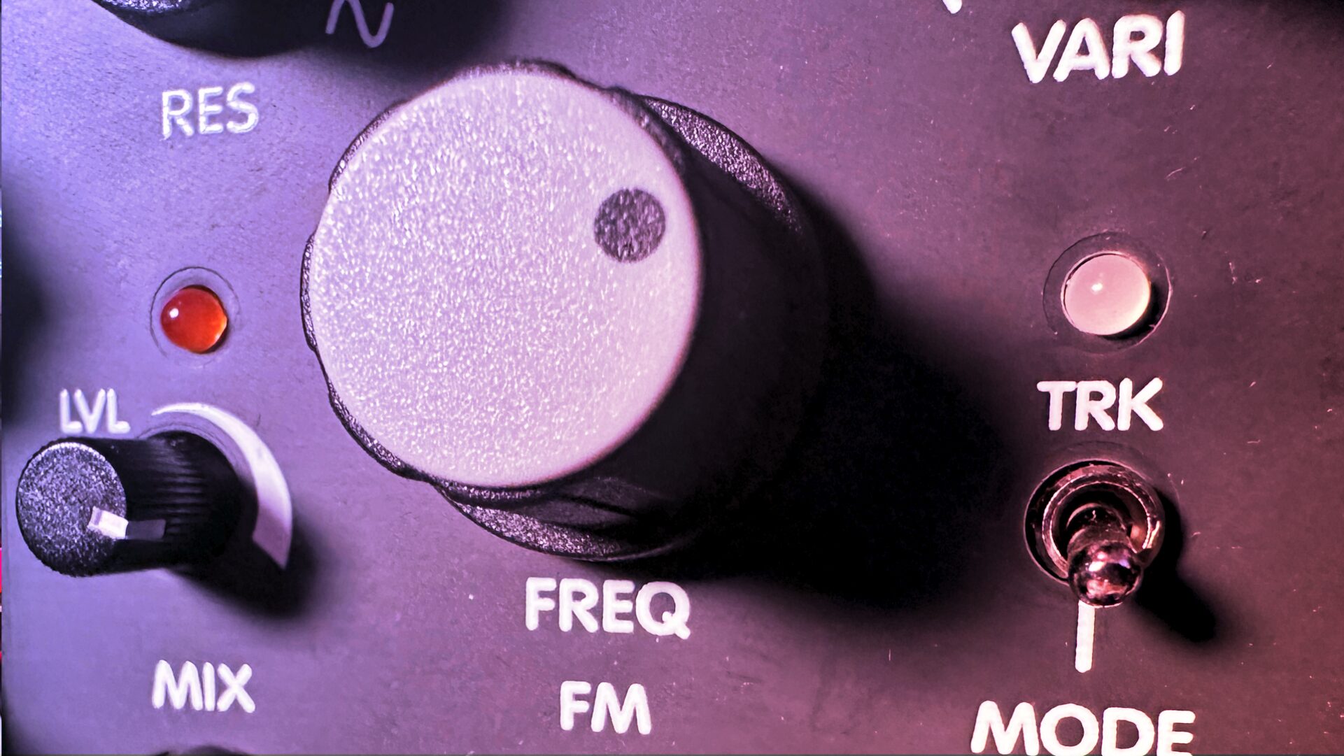 Close-up of a Eurorack filter with a large knob and Freq, Res, and Mode controls in purple light