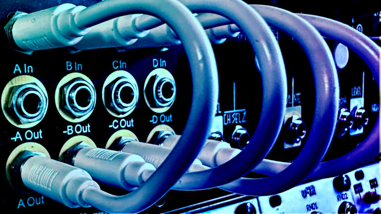 Close-up of blue patch cables plugged into a row of In and Out jacks