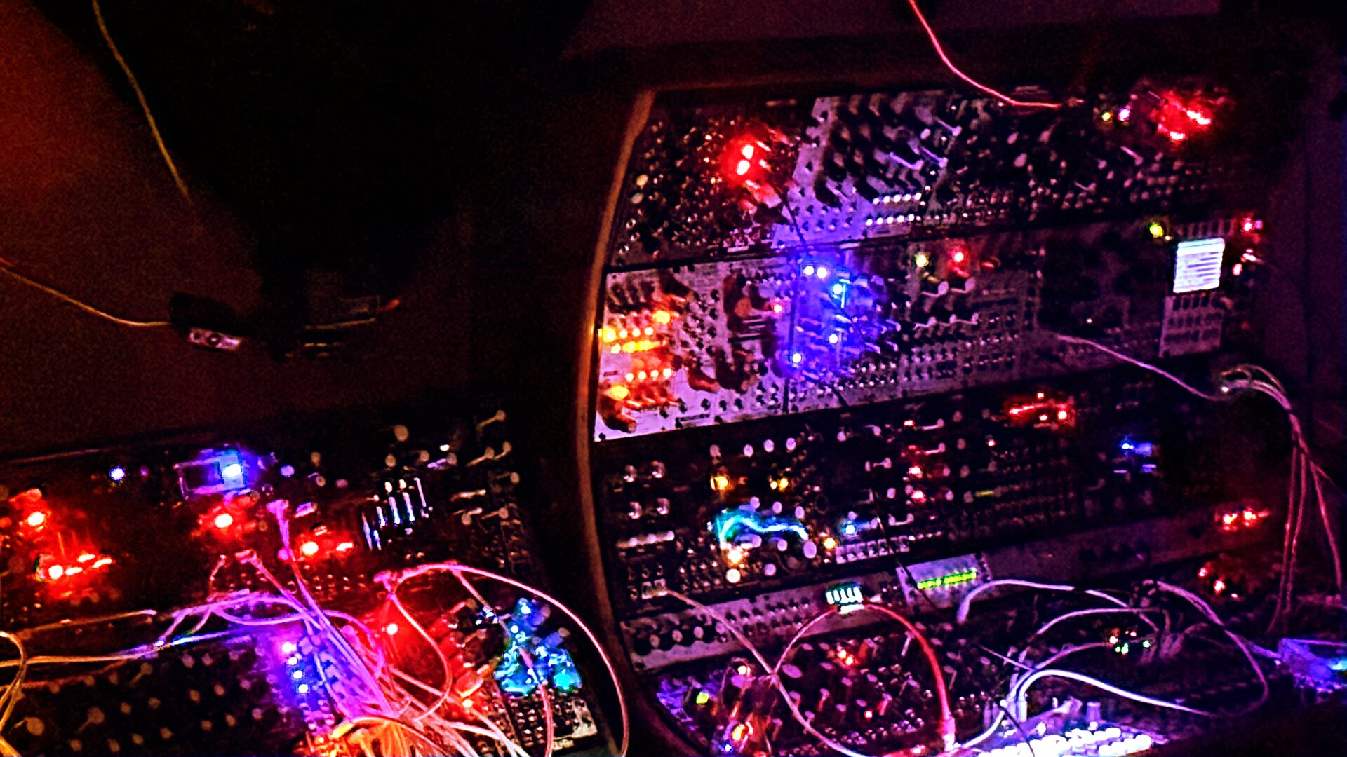 Eurorack live case with red and purple lights and patch cables in a dark room