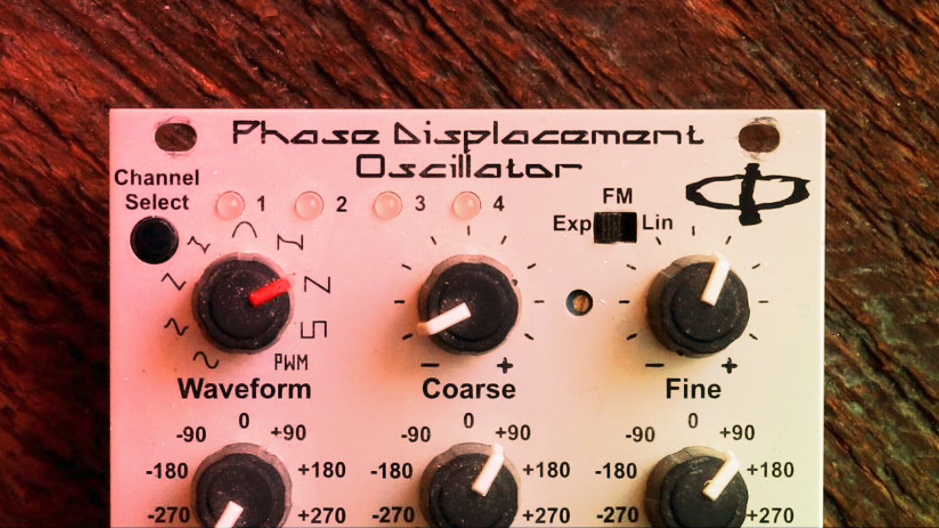 Close-up of the Phase Displacement Oscillator panel with Waveform, Coarse, and Fine knobs on a wood background