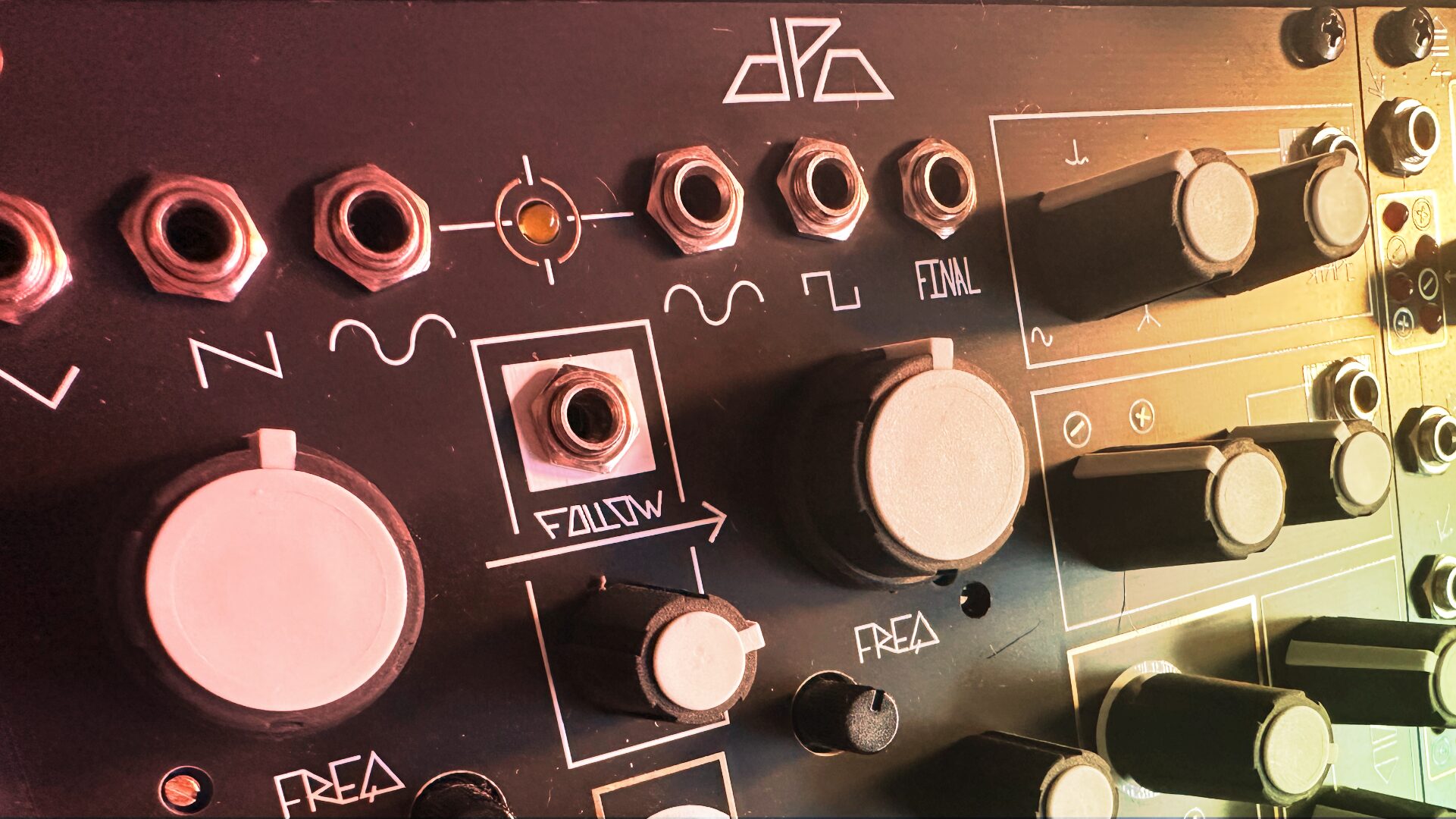 Close-up of a Eurorack panel with a large pink knob and jacks in warm light