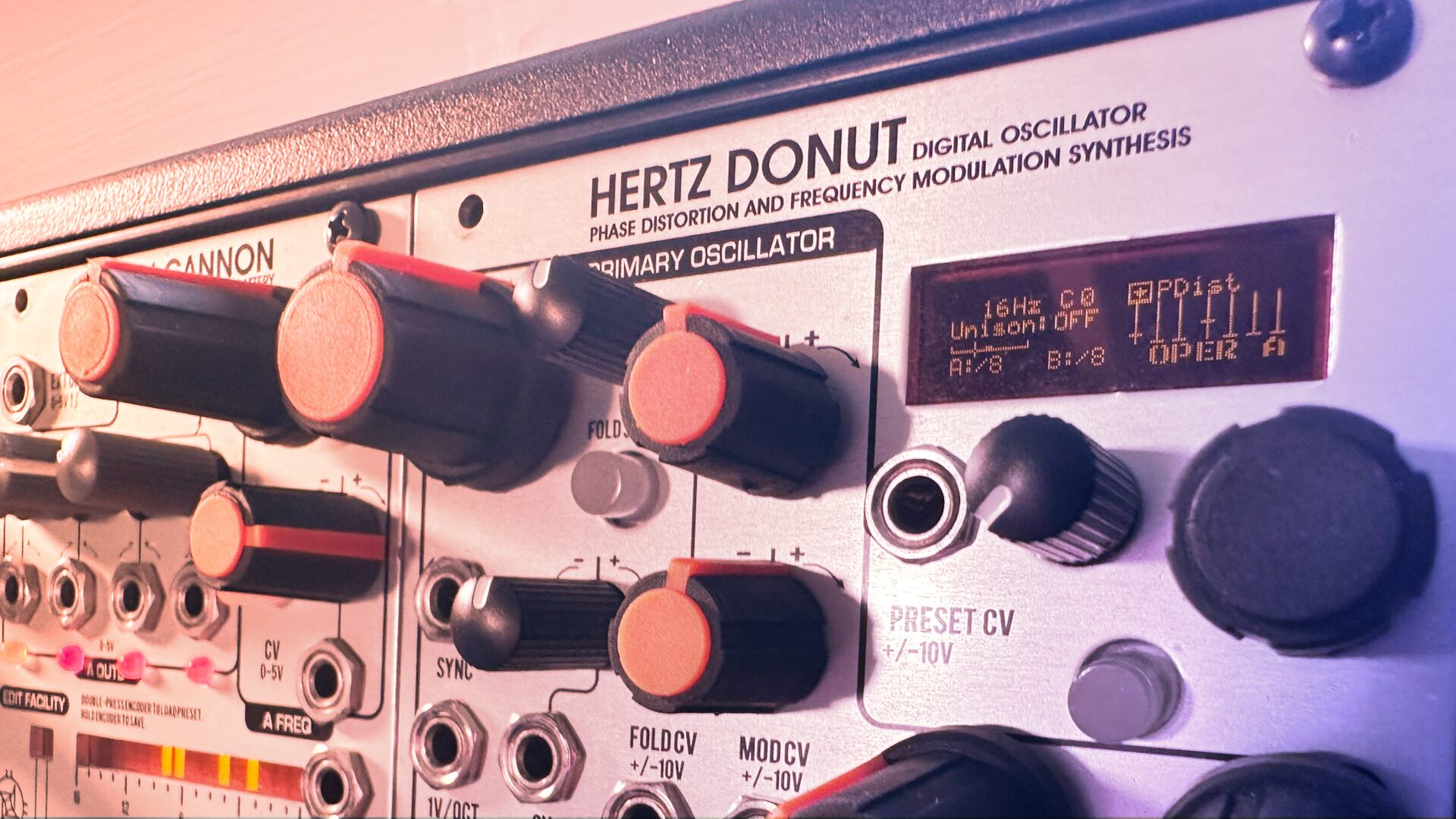 Close-up of the Hertz Donut MKIII panel with orange knobs in pink light