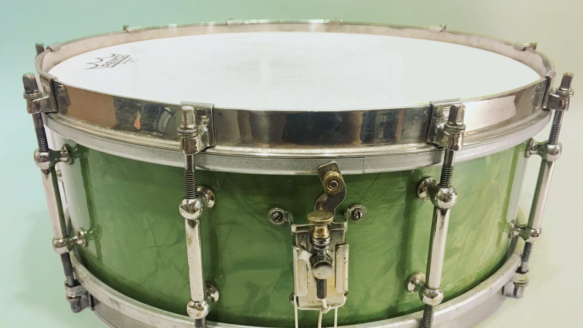 Green sparkle snare drum with a metal rim on a white background