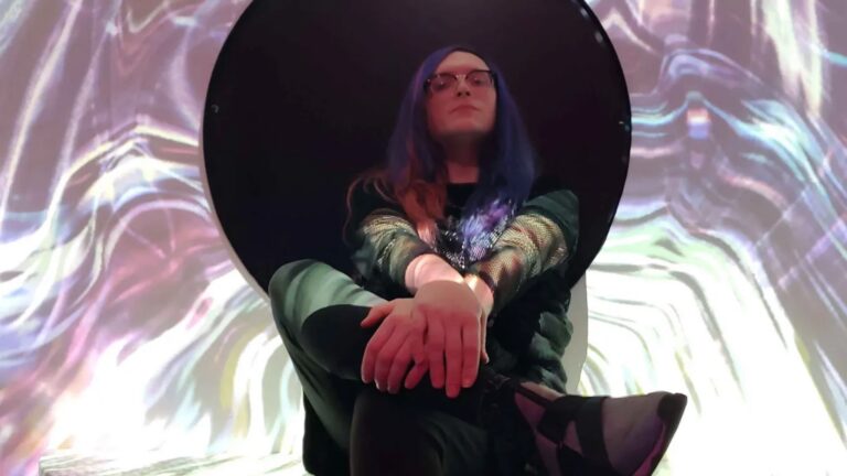 Mother Dessi seated in front of a swirling colorful backdrop