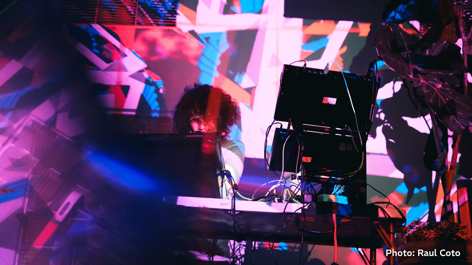 Performer at a modular synth setup under purple and blue stage lighting