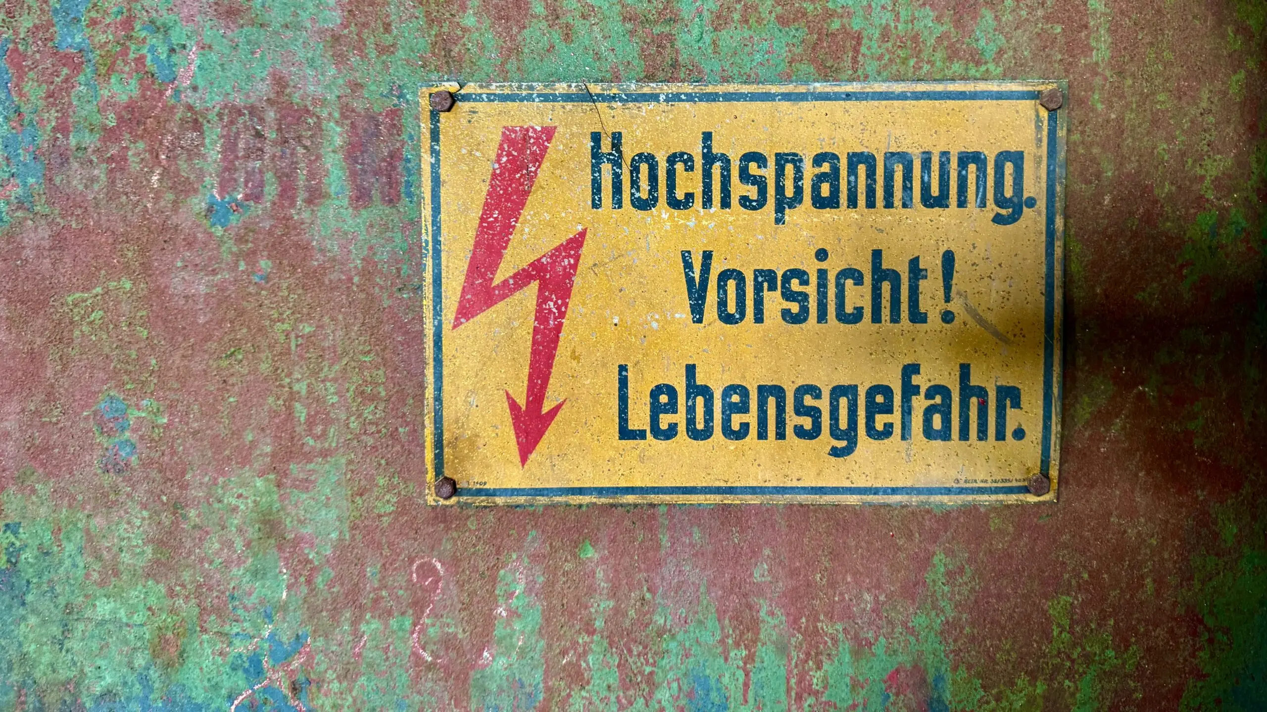 Yellow German high voltage warning sign on a weathered wall
