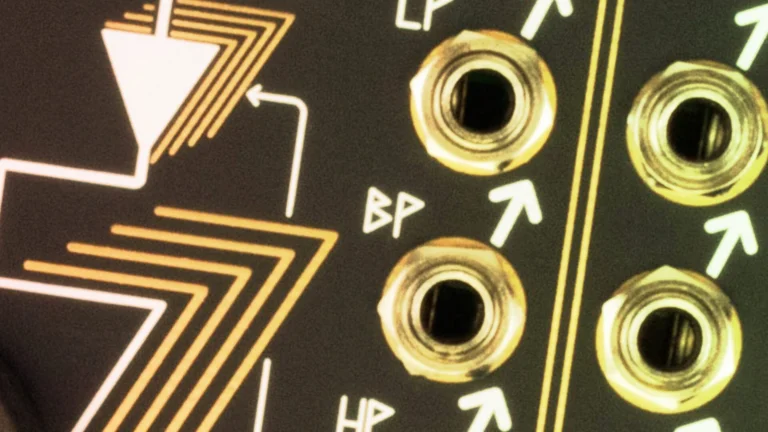 Close-up of gold-ringed jacks on a Eurorack panel with band pass symbols