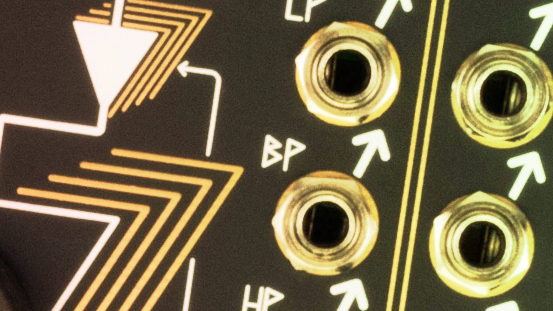 Close-up of gold-ringed jacks on a Eurorack panel with band pass symbols