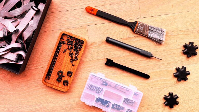 Eurorack hardware bits on a table including screws, a paintbrush, drivers, and parts organizers