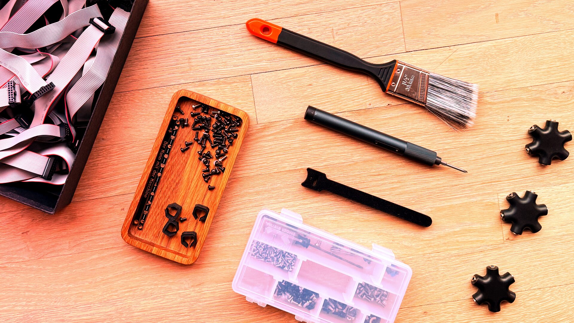 Eurorack hardware bits on a table including screws, a paintbrush, drivers, and parts organizers