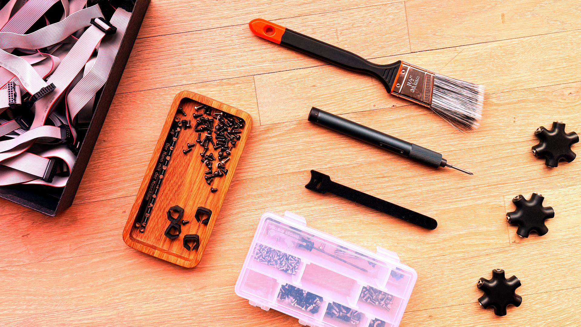 Eurorack hardware bits on a table including screws, a paintbrush, drivers, and parts organizers