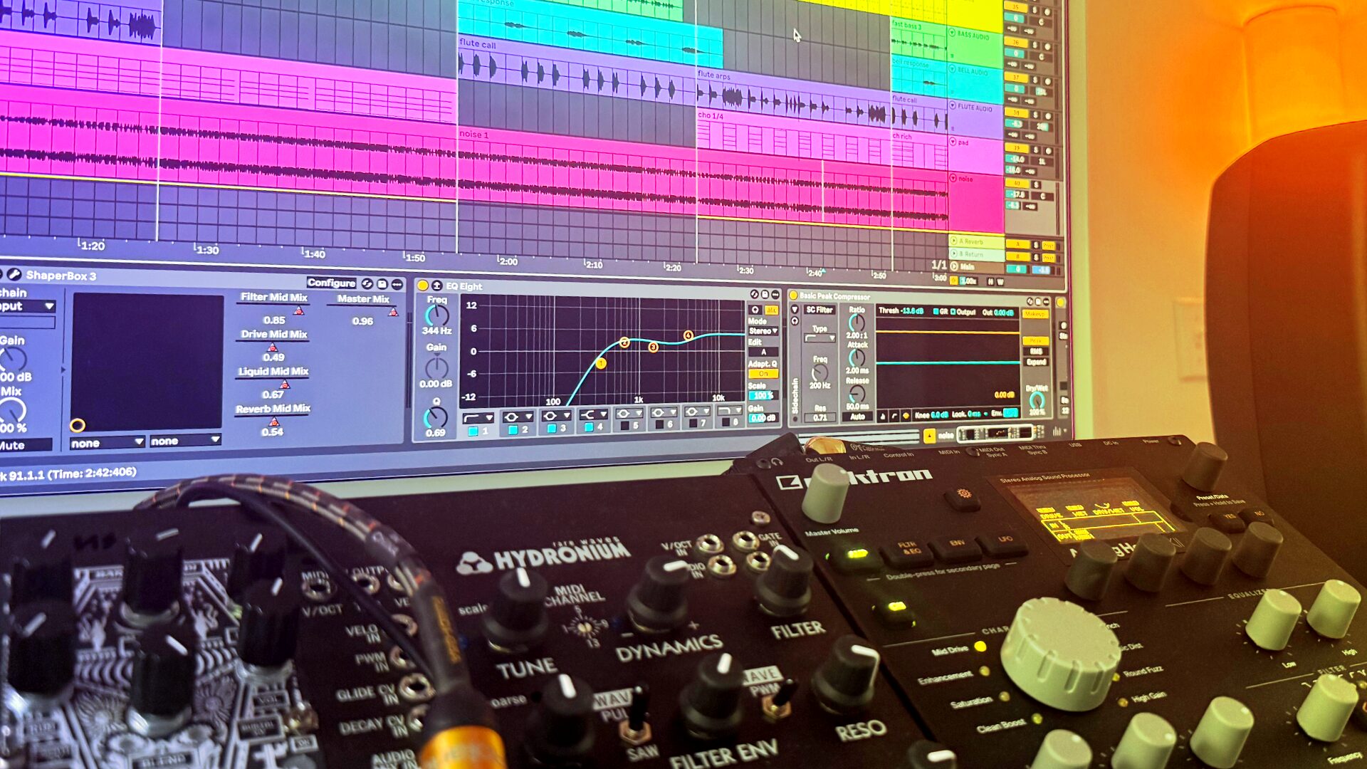 DAW window with recorded tracks above a Eurorack system lit in orange